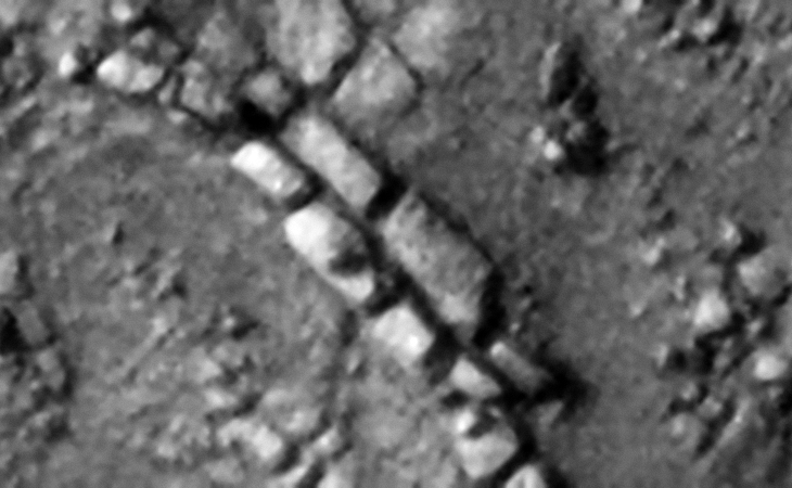 Two rows of rectangular megalithic blocks, smaller features or knobs can be seen on two of the blocks