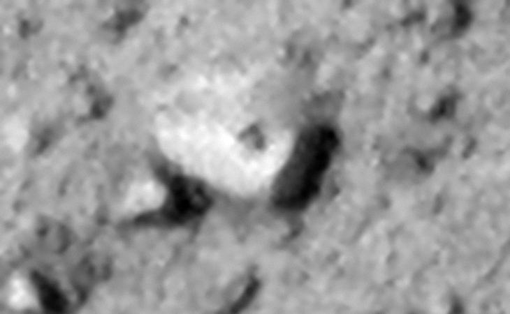 Partially buried megalithic block with two sides visible, note the strange dark feature on the one side