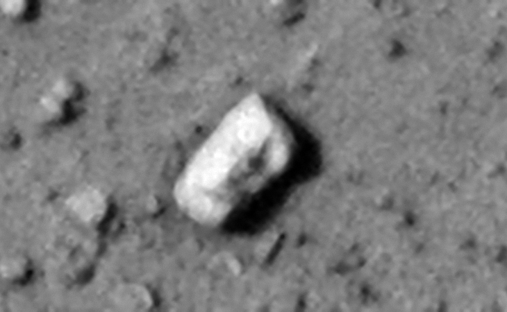 Eroded rectangular megalithic block with small dome-shaped feature or knob visible on the one side
