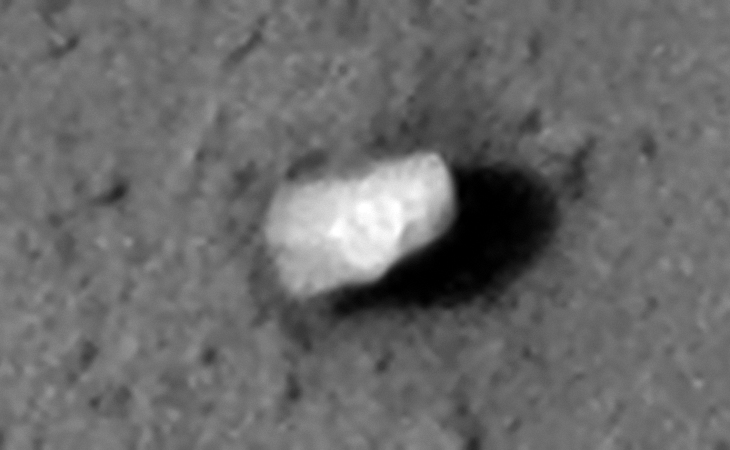 Megalithic block with small features or possibly symbols on the side. Seen is a circular feature with small triangular parts to the left and two small square outlines to the right
