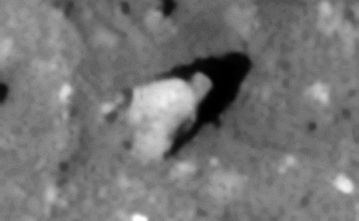 Partially buried machine parts, seen is a long narrow rectangular object sticking through a circular object