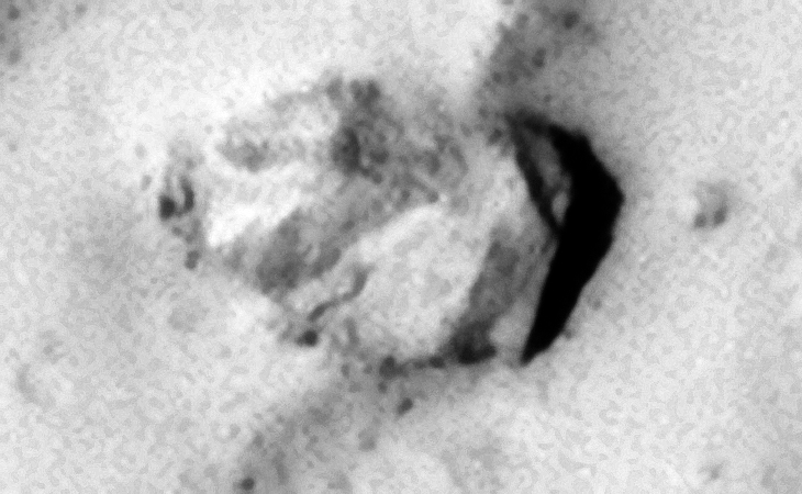 Smashed part of a structure with straight edges, one corner is at and angle with a part visible lower to the surface