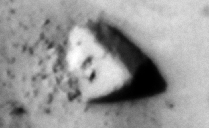 Triangular megalithic-looking block with a small triangular feature on the one side and a square area cut into the top right