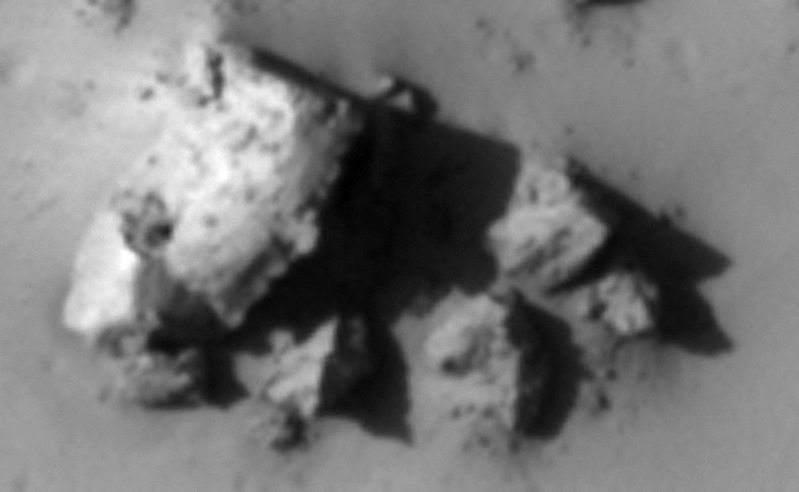 Wreckage or a structure of some kind, looks almost metallic? Check out the right-hand edge of the largest piece, it also seems to be a small hole towards the bottom left