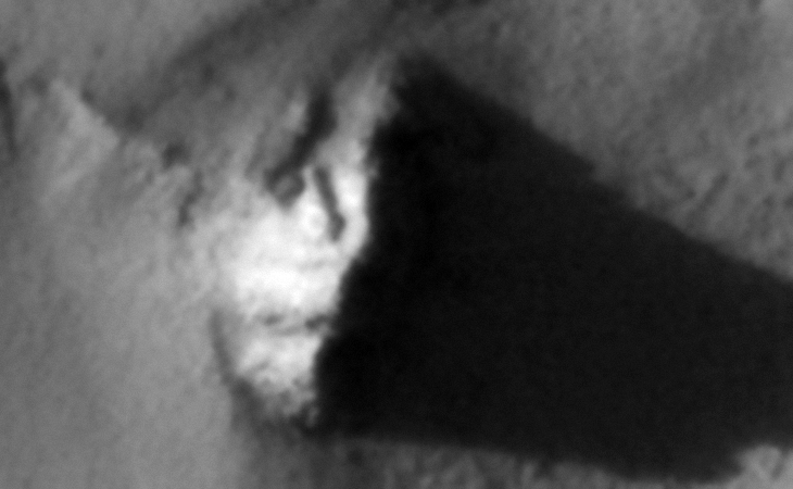 A metallic-looking object embedded in the surface with a small circular feature and short pipe on top, perhaps a shelter or underground entrance-way?