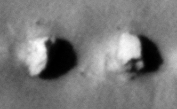 Two half-buried objects, the one to the left looks like a wing and the other on the right is a rectangular object with an opening or slot in the bottom side